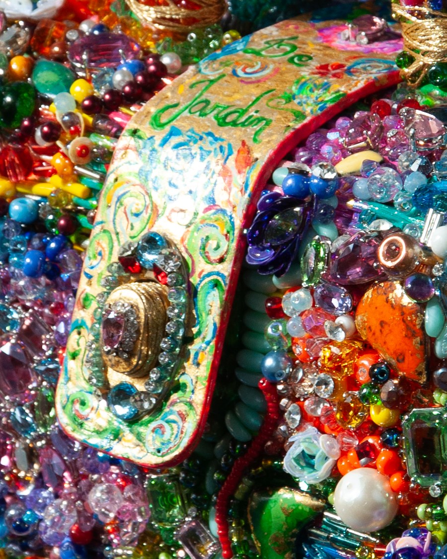 Détail du Jardin de Pierres : fermoir peint sur cuir portant les mots « Le Jardin », entouré de cristaux et de perles.