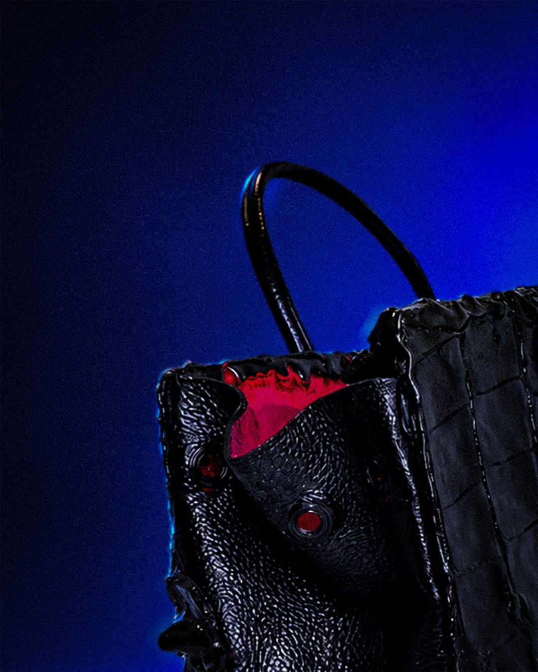 Secret du Nil — gros plan sur une anse noire et l’intérieur fuchsia, entre les œillets du cuir grainé.